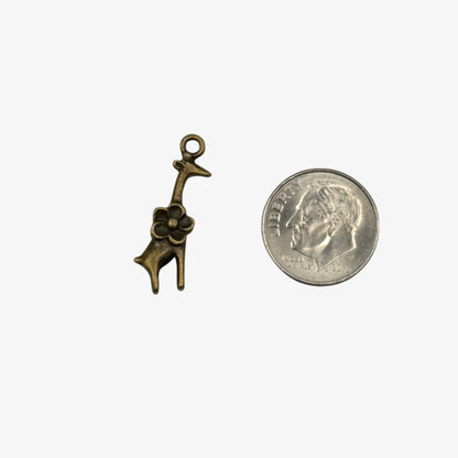 Bronze giraffe charm next to a quarter on a white background