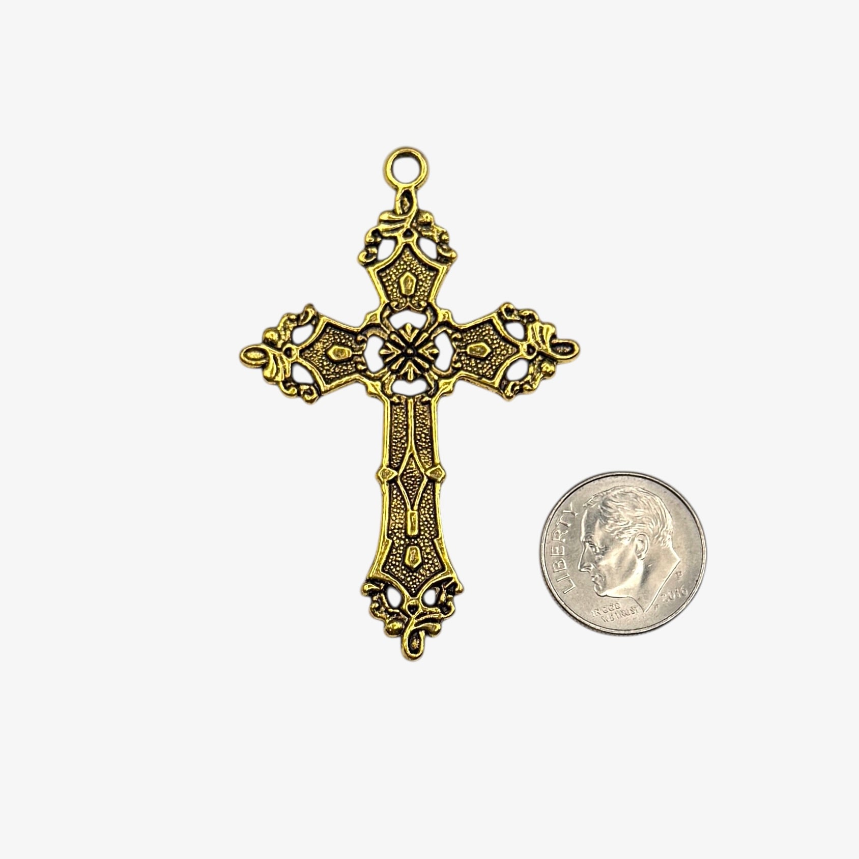 Gold cross pendant next to a coin on a white background