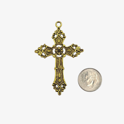 Gold cross pendant next to a coin on a white background