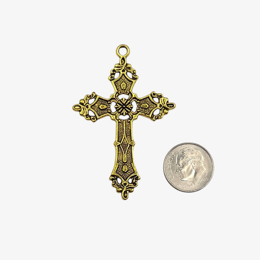 Gold cross pendant next to a coin on a white background
