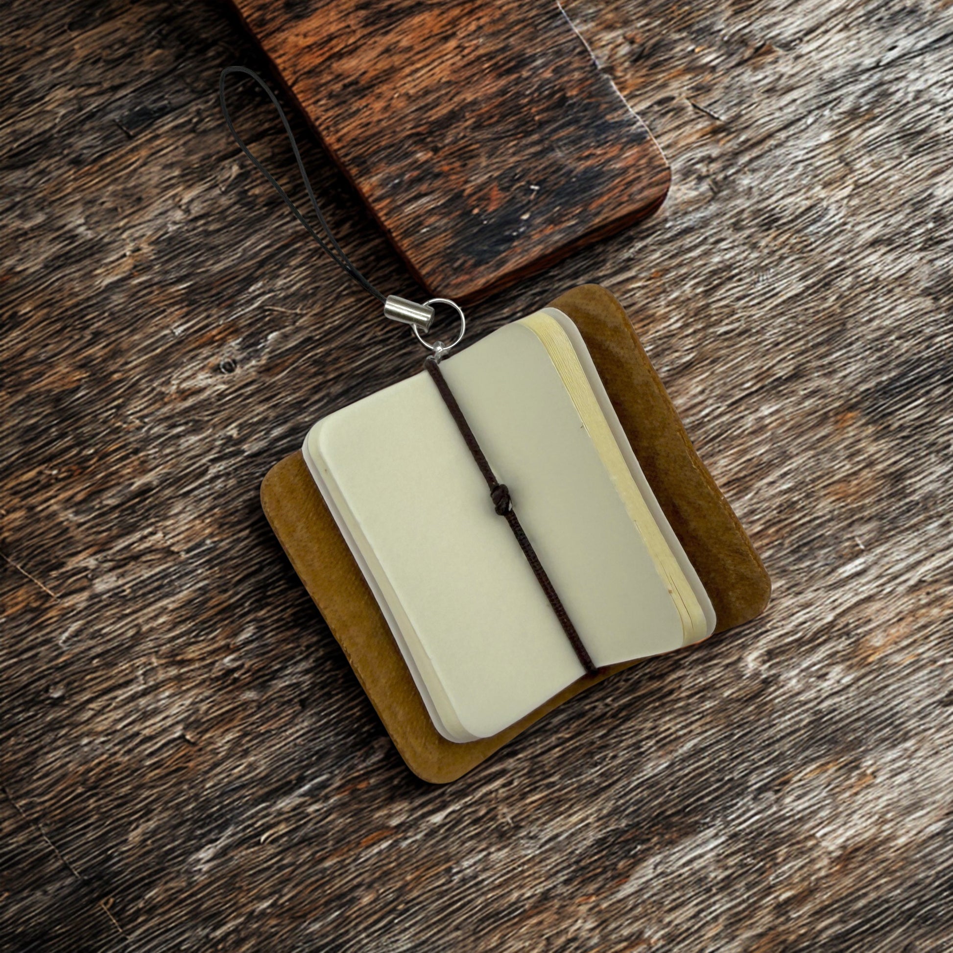 Small open book with a brown cover on a wooden surface