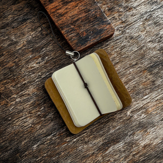 Small open book with a brown cover on a wooden surface