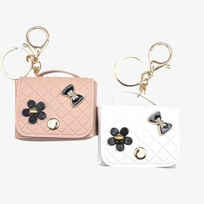 Two keychains shaped like small handbags with floral and bow designs on a white background.