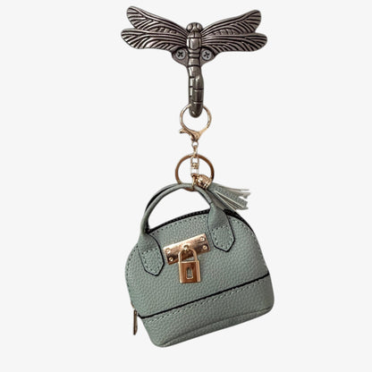 Keychain with a miniature handbag and dragonfly design on a white background