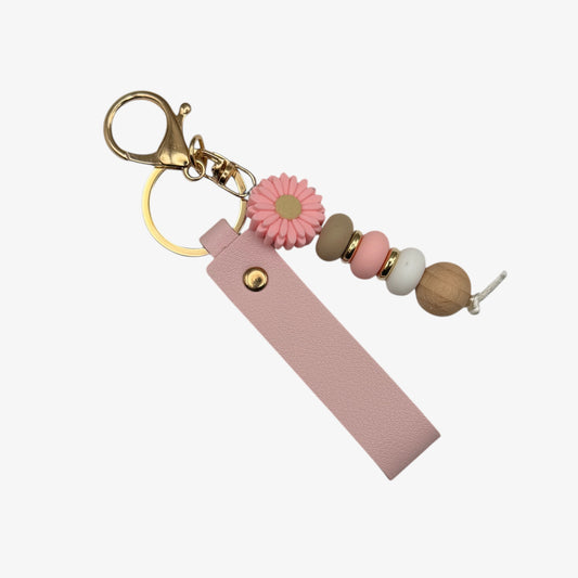 Keychain with pink flower, beads, and gold ring on a white background