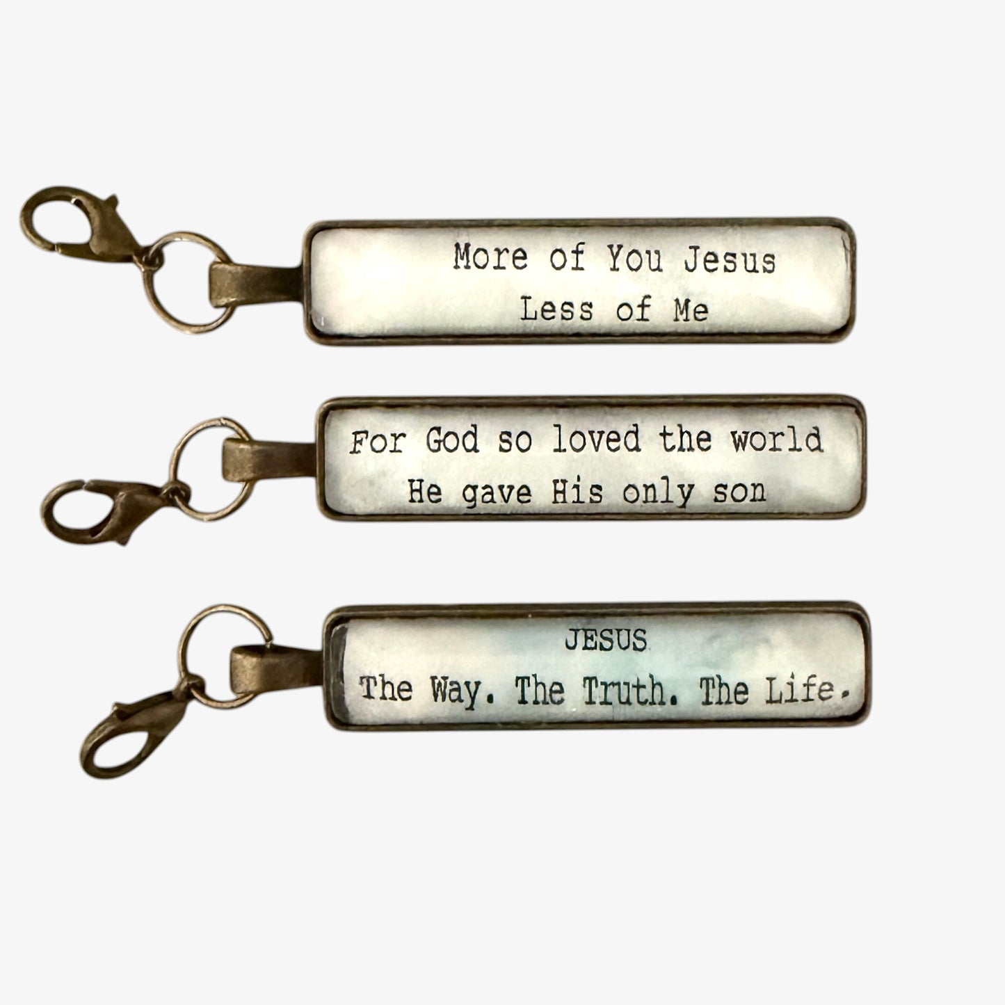 Three keychains with religious inscriptions on a white background