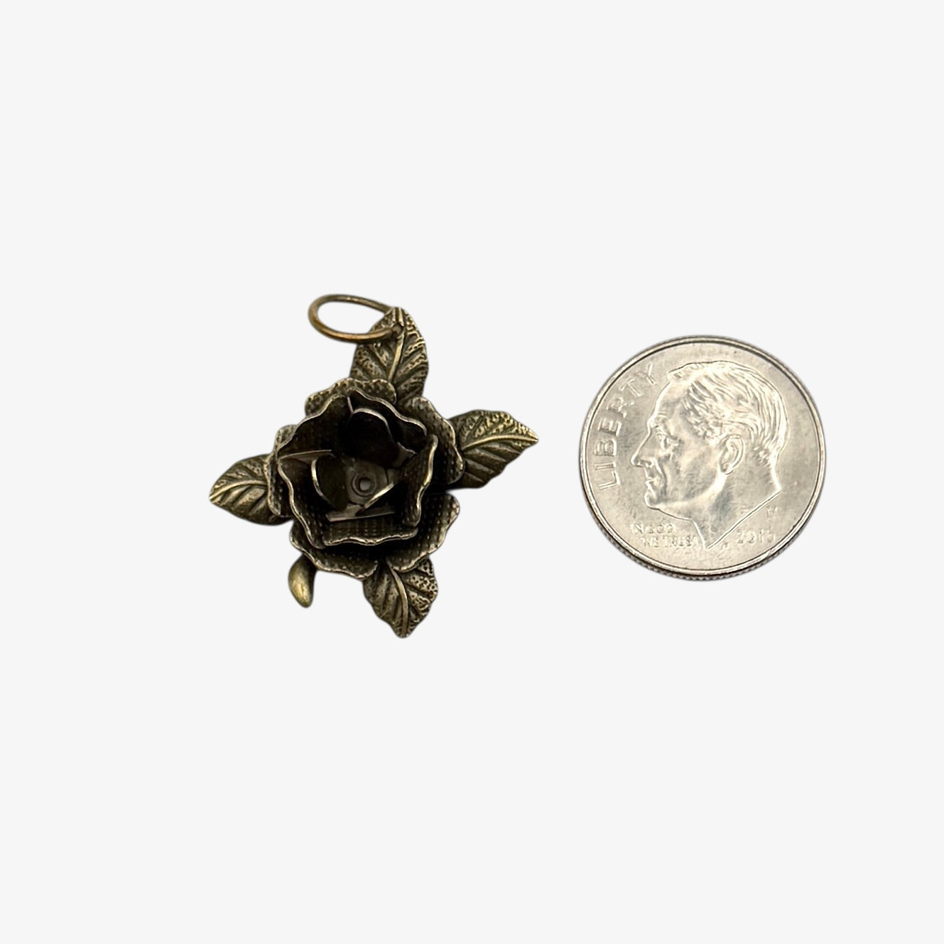Bronze rose pendant next to a quarter for scale on a white background