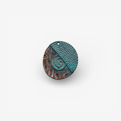 Round antique copper and turquoise pendant with a spiral design on a white background