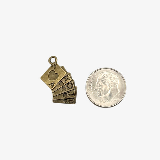 Bronze playing card charm next to a coin on a white background