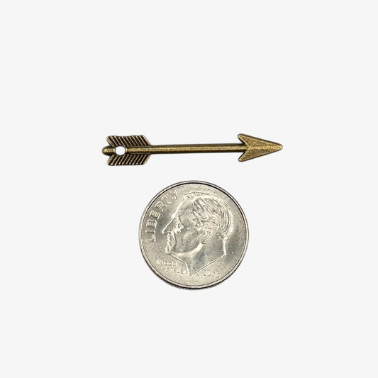 Small bronze arrow-shaped object next to a U.S. quarter coin on a white background