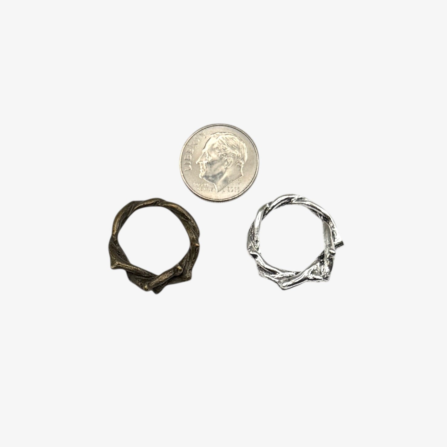 Two small metal rings next to a quarter on a white background